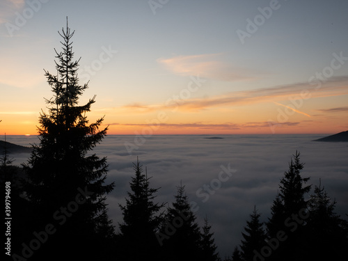 View from mountain range to the valley above fog and clouds at sunset