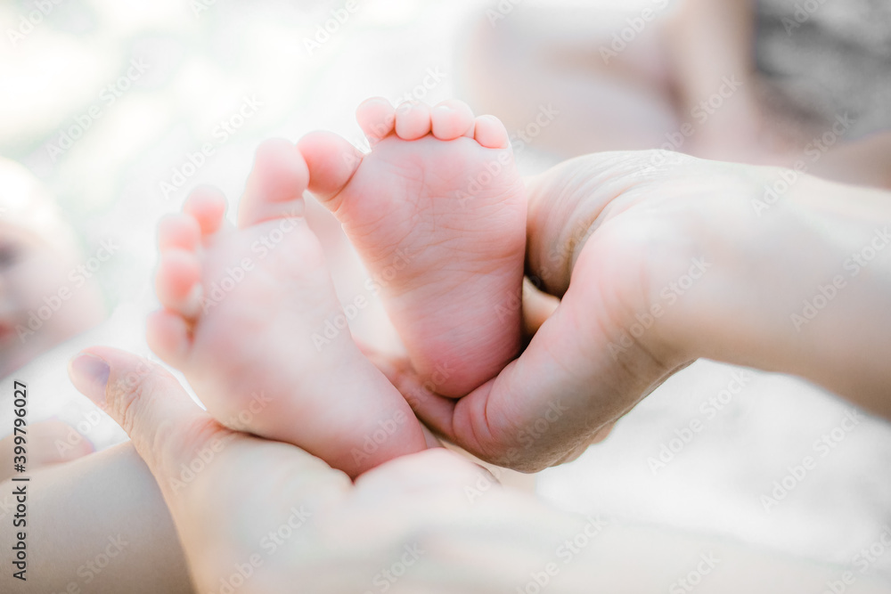 The mother gently holds her baby's small feet in her hands. The love and feelings of a parent for their newborn child. Close-up The mother gently holds her baby's small feet in her hands. The love and feelings of a parent for their newborn child. Close-up