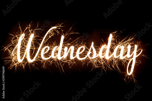 Cursive word of 'Wednesday' in dazzling sparkler effect on dark background
