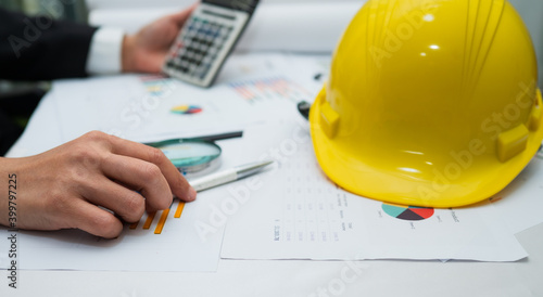 Architect or engineer working project accounting with graph and construction helmet in office, Construction account concept.