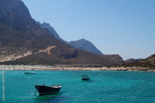 Coast on a sunny day, turquoise clear water and boats.
