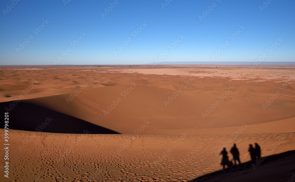 Silhouette von Menschen auf einer Sanddüne mit Blick auf die Wüste