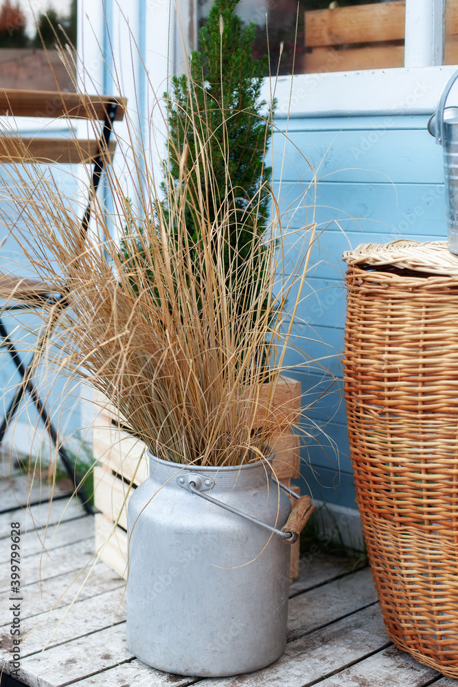 Wicker basket Near bouquet of dried flowers on wooden porch. Dried  spikelets and pampas grass in