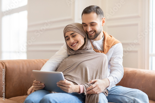 Muslim Couple Using Tablet Watching Movie Online Sitting At Home