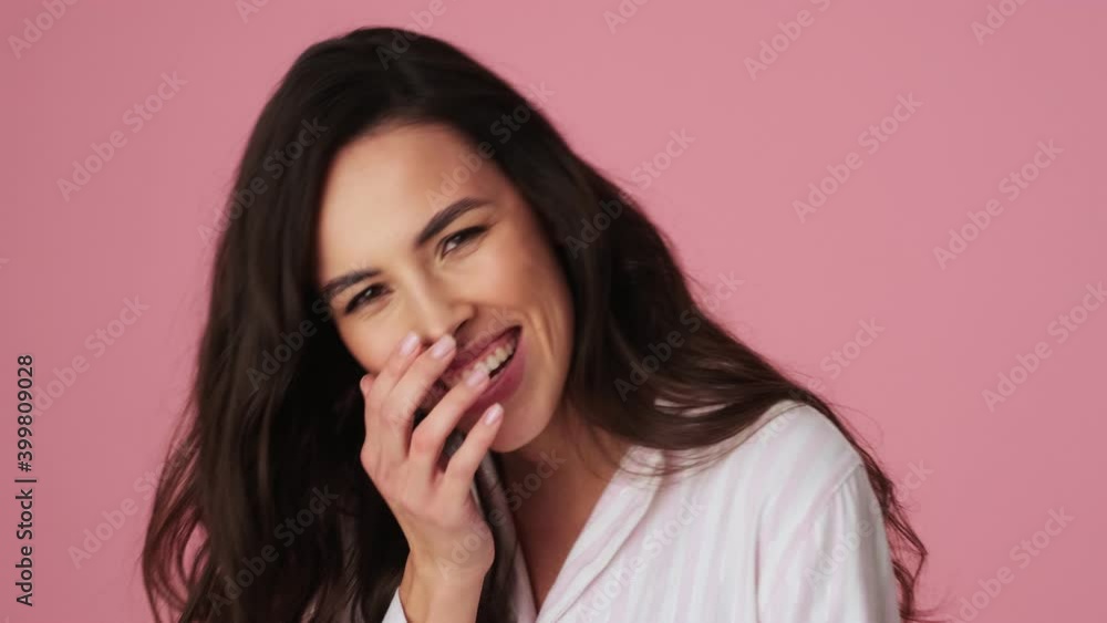A positive young woman is laughing standing isolated over a pink background in the studio A positive young woman is laughing standing isolated over a pink background in the studio