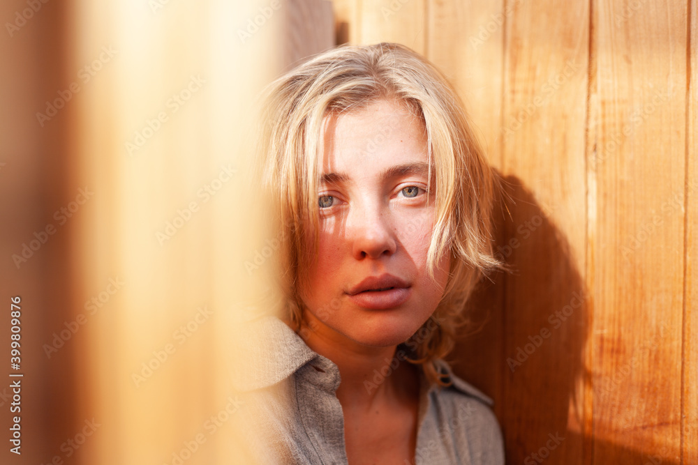 soft portrait of beautiful young blonde woman without make-up in gray linen shirt in wooden interior with sunlight soft portrait of beautiful young blonde woman without make-up in gray linen shirt in wooden interior with sunlight
