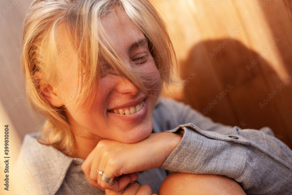 soft portrait of beautiful young blonde woman without make-up in gray linen shirt in wooden interior with sunlight soft portrait of beautiful young blonde woman without make-up in gray linen shirt in wooden interior with sunlight