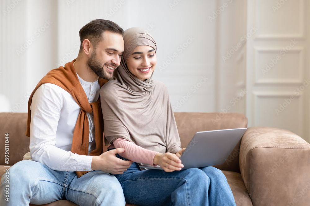 Happy Married Arab Couple Watching Movie On Laptop At Home