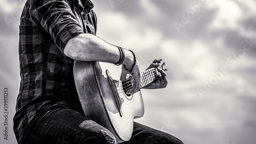 Man's hands playing acoustic guitar, close up. Acoustic guitars playing. Music concept. Black and white