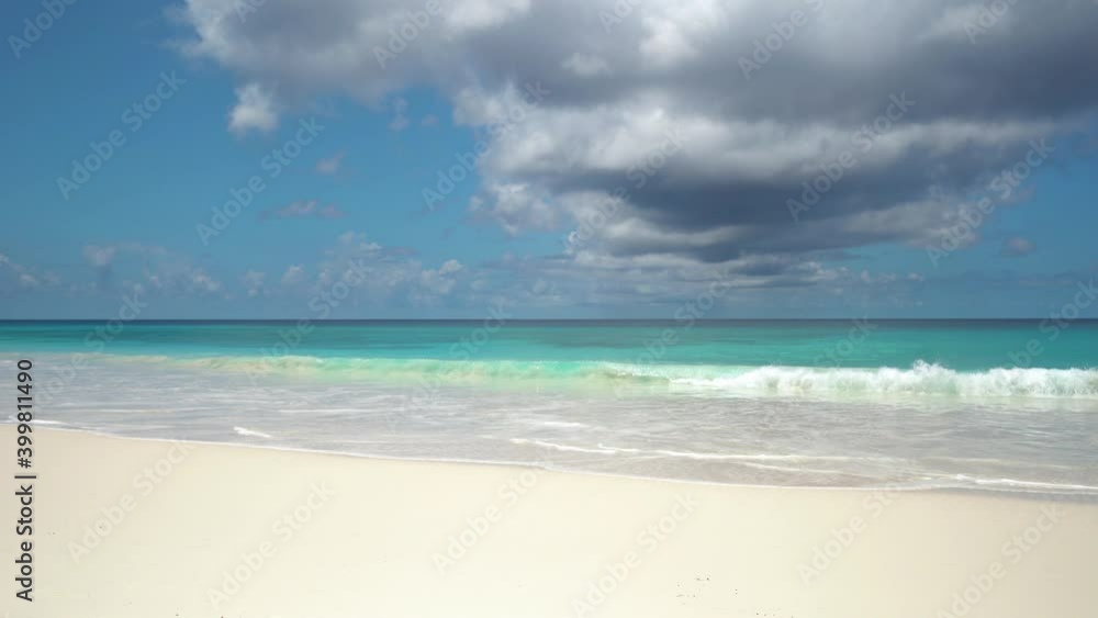 Exotic beach by the ocean with rolling waves on the sandy shore and blue sky Exotic beach by the ocean with rolling waves on the sandy shore and blue sky