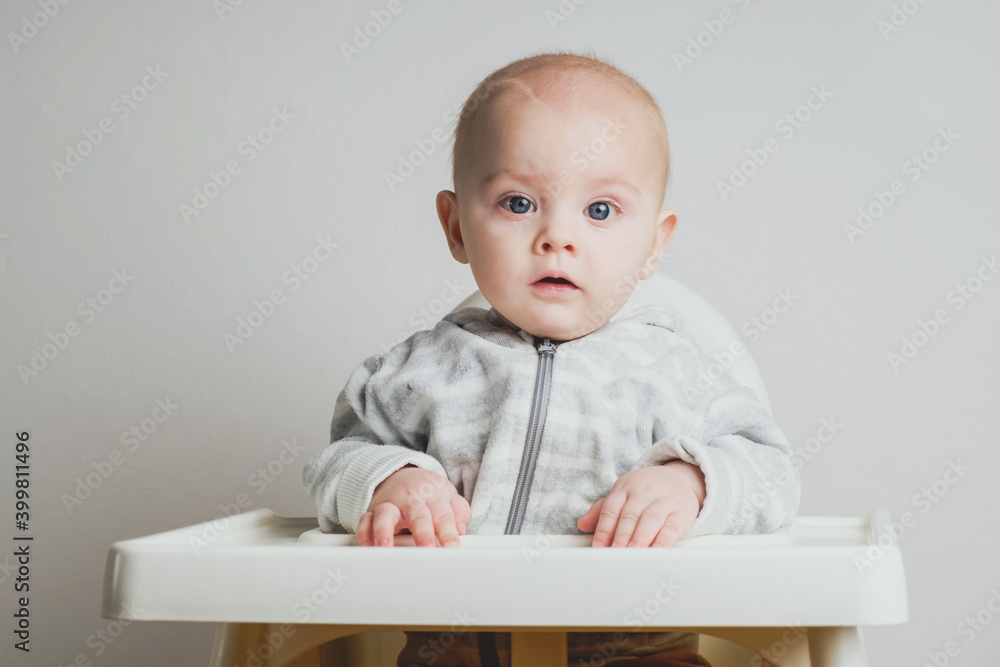 Caucasian 8 month old infant baby boy sitting in a baby's high chair. Caucasian 8 month old infant baby boy sitting in a baby's high chair.