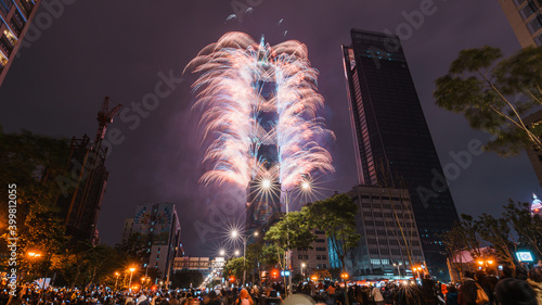 Taipei City Night landscape and Taipei 101 skyscraper is lit up by fireworks. People watching and taking photos and videos around buildings to celebrate the new year event. photo