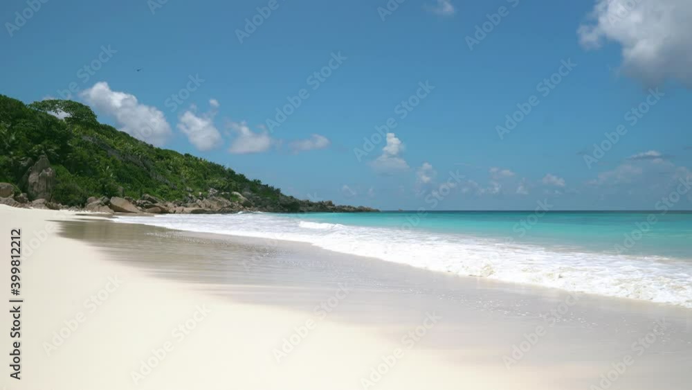 Exotic beach by the ocean with rolling waves on the sandy shore and blue sky Exotic beach by the ocean with rolling waves on the sandy shore and blue sky
