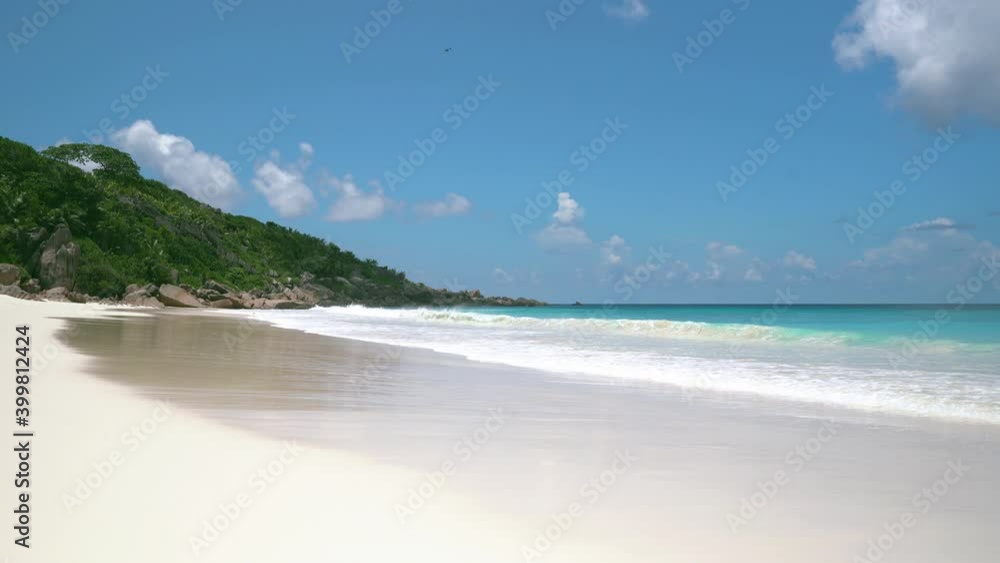 Exotic beach by the ocean with rolling waves on the sandy shore and blue sky Exotic beach by the ocean with rolling waves on the sandy shore and blue sky