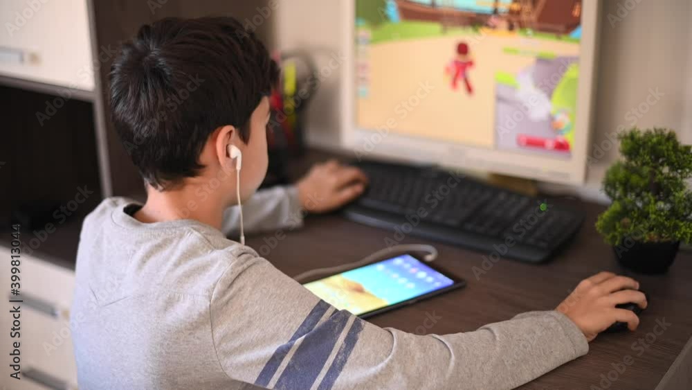 Kid playing video games at desktop computer at home, listening to music Kid playing video games at desktop computer at home, listening to music