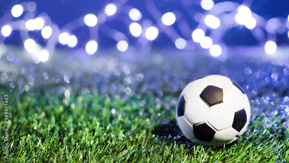 Fototapeta premium Traditional soccer ball on grass soccer field at night over winner bokeh.