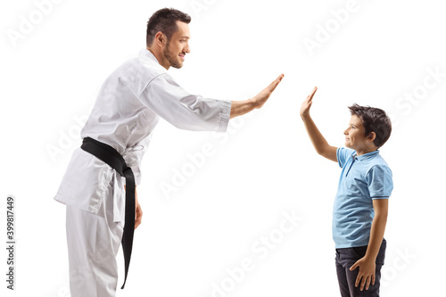 Man in karate kimono gesturing high-five with a child