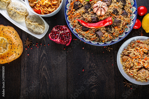 The concept of oriental cuisine. Assorted Uzbek food set, pilaf, samsa, lagman, manta, shurpa central asia food. Homemade Uzbek pilaf or plov from lamb served in cast iron cookware