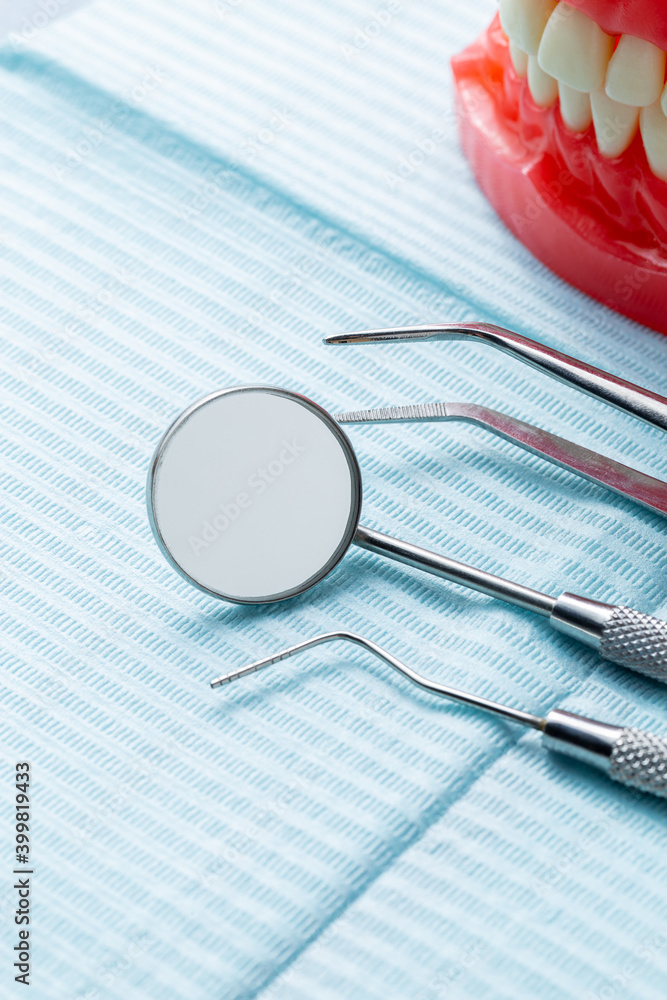 A group of dental instruments and a model of a mouth on a blue dental napkin A group of dental instruments and a model of a mouth on a blue dental napkin