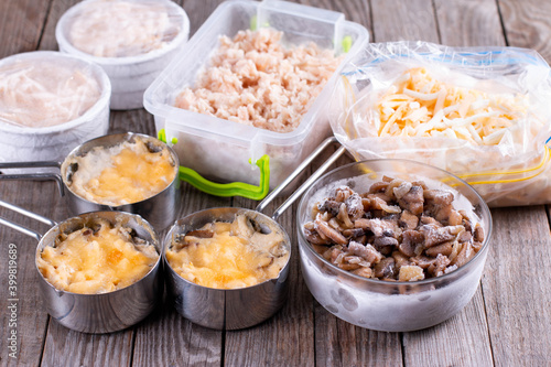 Frozen food. French dish julienne. Mushroom, chicken and cheese gratin in bowls on wooden table