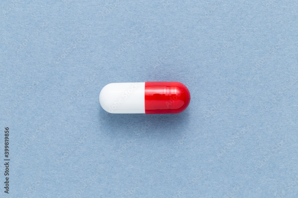 A red and white medicine capsule on a blue background A red and white medicine capsule on a blue background