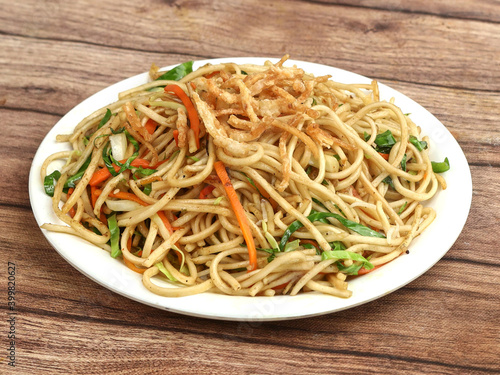 Veg Hakka Noodles a popular oriental dish made with noodles and vegetables, served over a rustic wooden background, selective focus