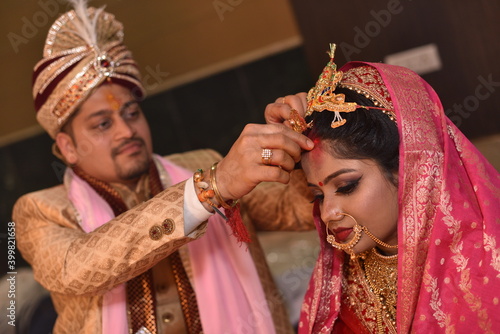 Groom applying sindoor also known as vermilion to bride during wedding ceremony as one of the rituals. This is a very auspicious activity of great importance during the ceremony  photo