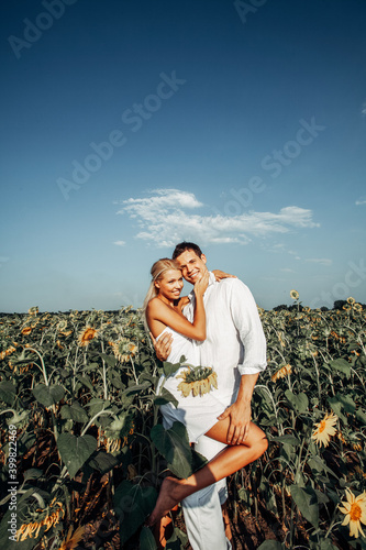 Happy beautiful young couple in a field of sunflowers