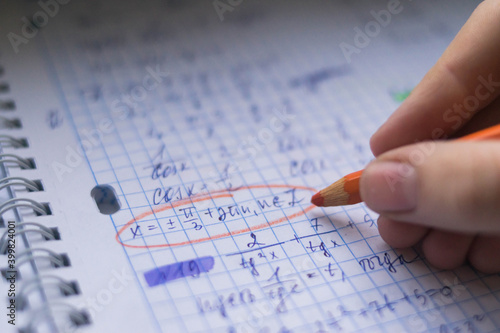 Office. Study. Man's hand writes with a colored pencil on paper. Formula sheet. Mathematics. Notebook on rings.