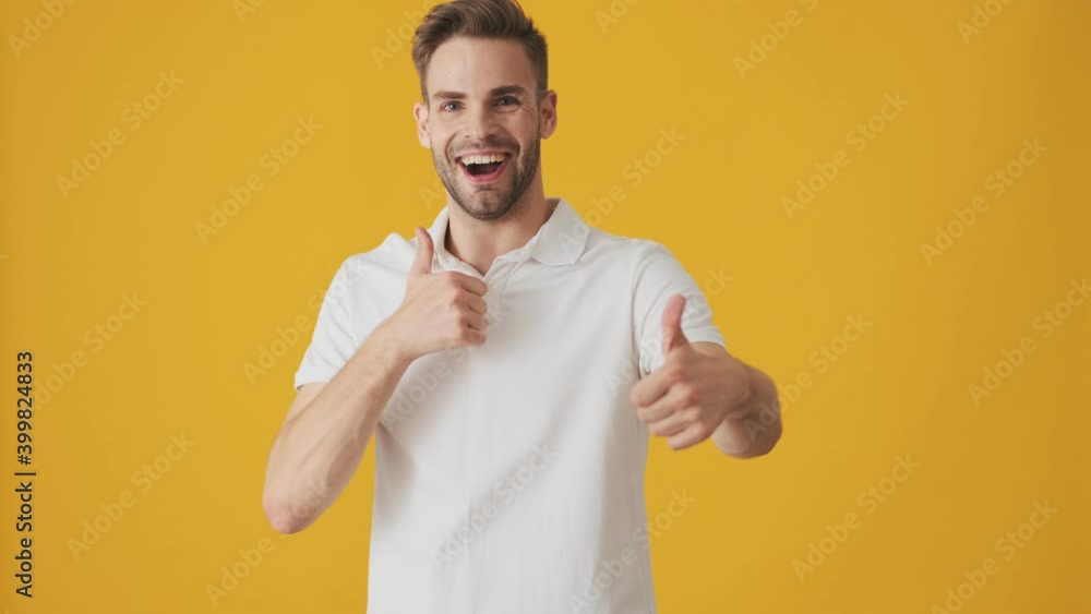 Handsome young positive man isolated over yellow wall background and showing thumbs up gesture Handsome young positive man isolated over yellow wall background and showing thumbs up gesture