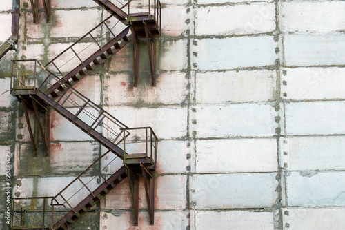 External metal staircase on the facade of an abandoned factory or enterprise building.