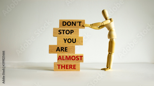 You are almost there symbol. Wooden blocks with words 'dont stop you are almost there'. Wooden model of human. Beautiful white background, copy space. Business and almost there concept.
