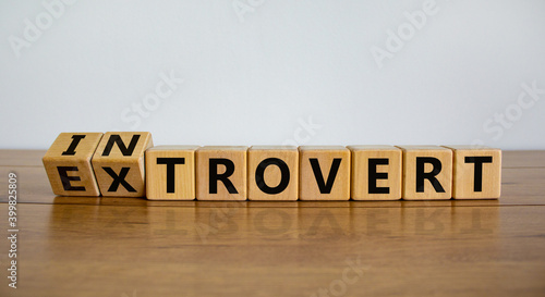 Introvert or extrovert symbol. Fliped cubes and changed the word 'introvert' to 'extrovert'. Beautiful wooden table, white background, copy space. Psychological and Introvert or extrovert concept. photo