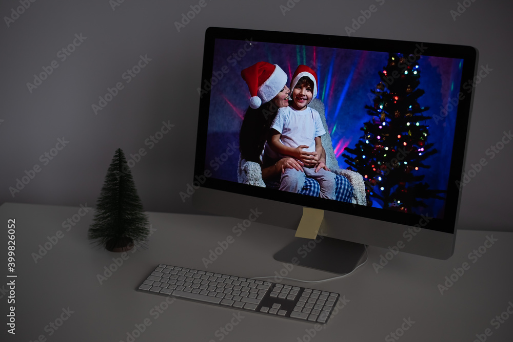 Mother and son in santa claus hats congratulate merry christmas on a video call on a computer Mother and son in santa claus hats congratulate merry christmas on a video call on a computer