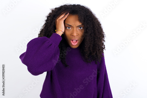 Embarrassed Young beautiful African American woman wearing knitted sweater against white wall with shocked expression, expresses great amazement, Puzzled model poses indoor © Roquillo