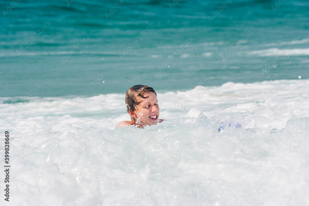 Teenage boy having fun with surfboard in waves of Atlantic Ocean Teenage boy having fun with surfboard in waves of Atlantic Ocean