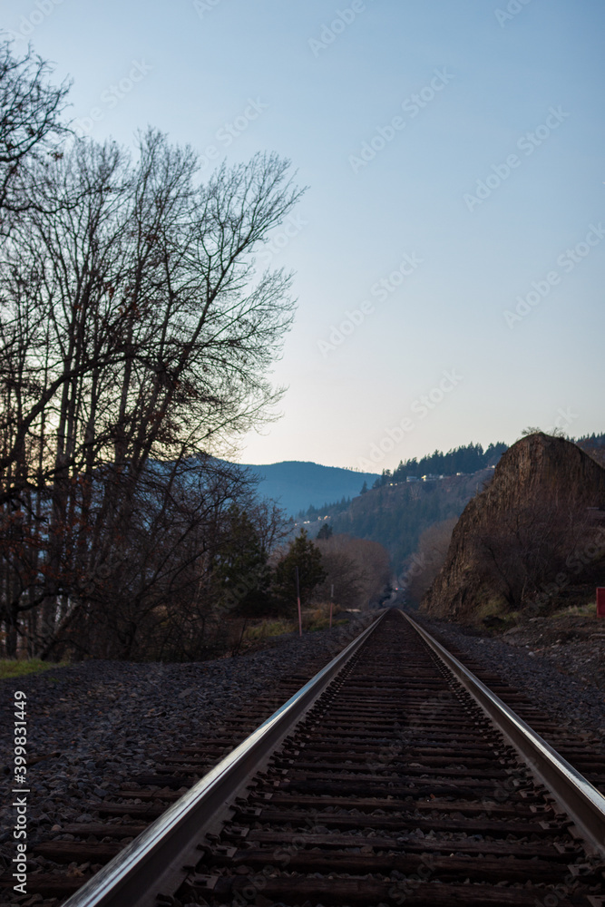 Fototapeta premium Landscape in late autumn at sunset, in the center of the railway, in front of the horizon blue mountains.