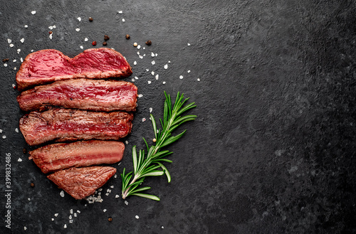Different degrees of roasting beef steak in heart shape with spices on a stone background with a copy of the space for your text.