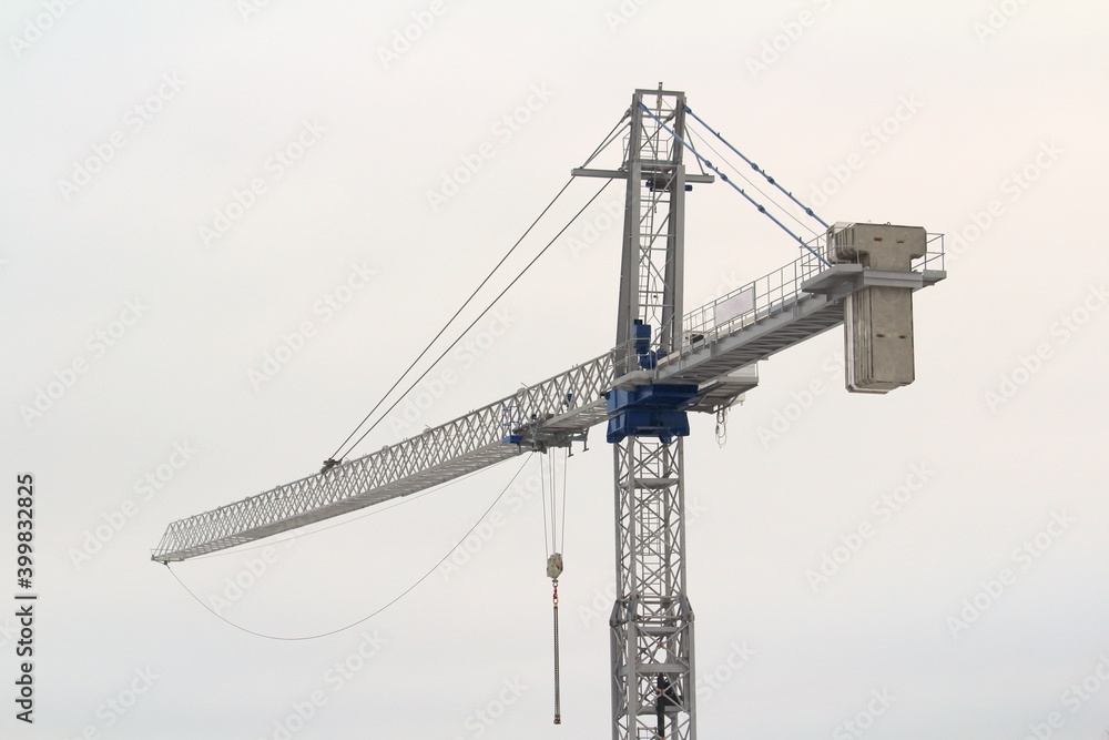 Tower crane works at a construction site against the blue cloud winter sky