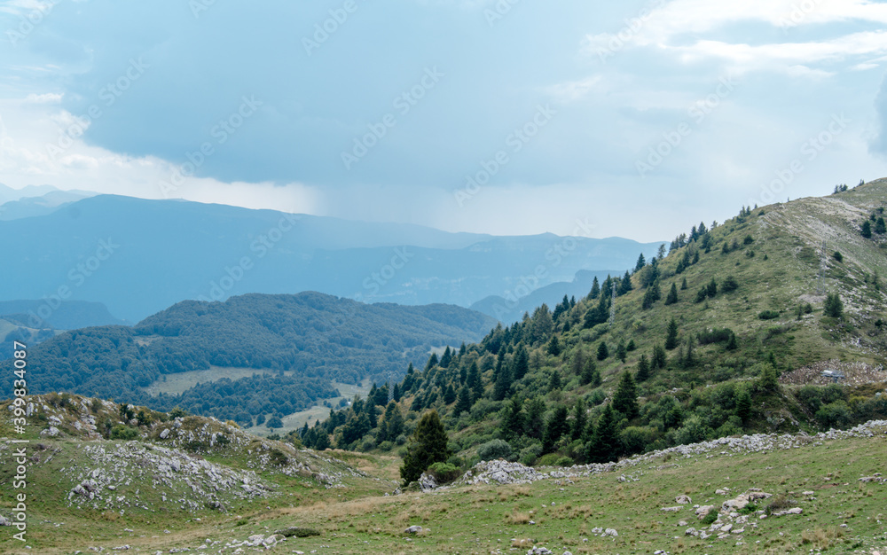 Beautiful view of the peaks of Monte Baldo. Stunning cloudy and panoramic view. Green Pastures in Italian Alps