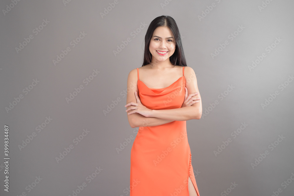 Fashion portrait of beautiful woman wearing orange dress isolated over gray background studio Fashion portrait of beautiful woman wearing orange dress isolated over gray background studio