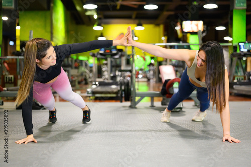 Two sporty women doing high five while workout push up exercise in Gym. High quality photo