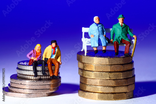 Conceptual image of miniature a figure couples sat on coins isolated against a blue background photo