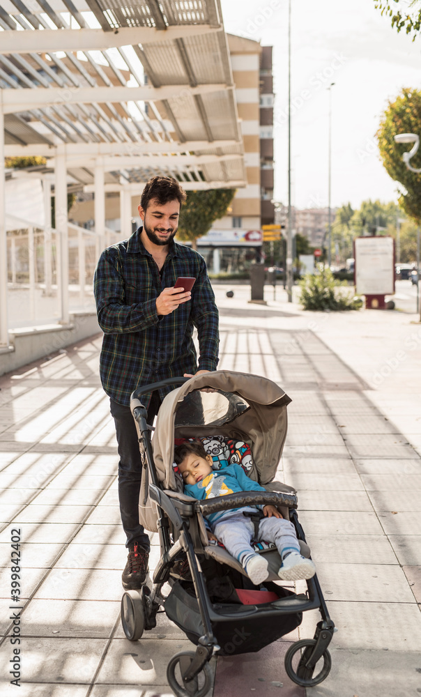Obraz premium Bearded man with his sleeping baby on car looking phone