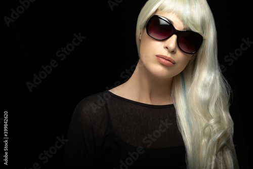Beautiful blond woman in sunglasses on black background