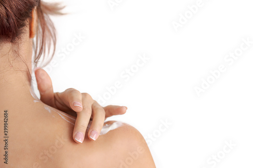 red hair woman's hand applying cream on her shoulder.  Concept of  smooth skin, skincare, cosmetics, wellness center, healthy lifestyle
