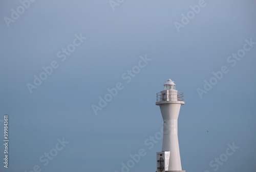 White lighthouse towering under the light blue sky