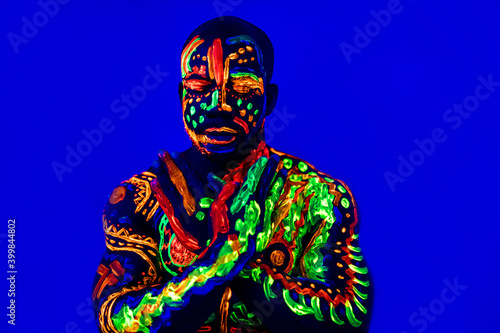 afro american man posing in studio shot with UV light © yurakrasil