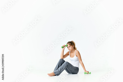 woman seroshtanov sits on the floor and a dumbbell in the background 
