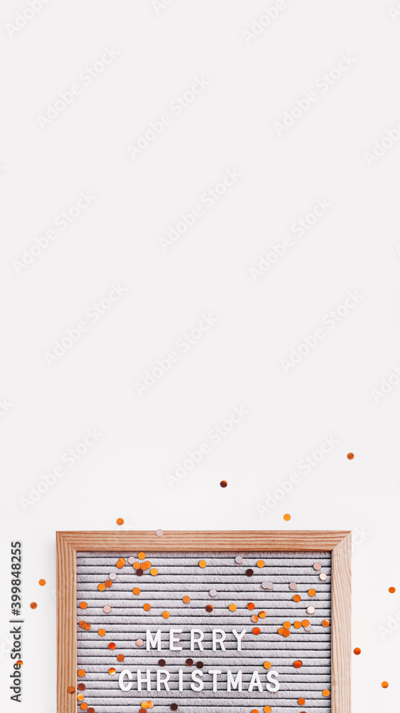 Letter board with Merry Christmas greeting and scattering golden confetti. New Year celebration. Copy space on white background. Vertical banner 9:16. Letter board with Merry Christmas greeting and scattering golden confetti. New Year celebration. Copy space on white background. Vertical banner 9:16.